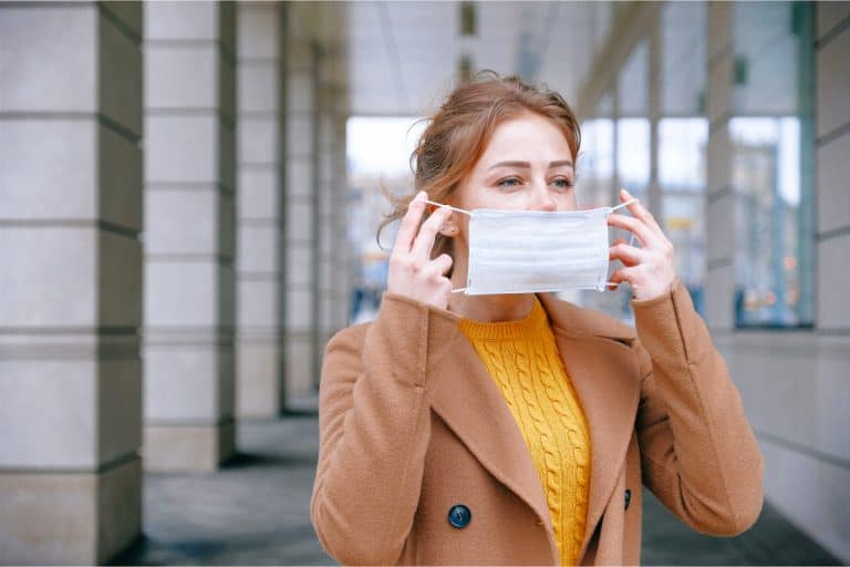 mujer tapandose la boca con una mascarilla