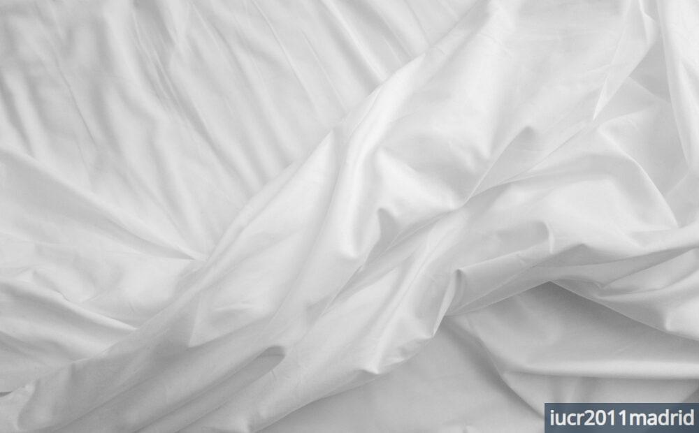 a black and white photo of a bed with white sheets